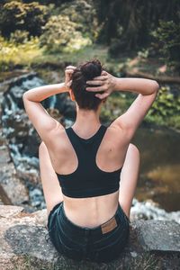 Rear view of woman sitting on rock