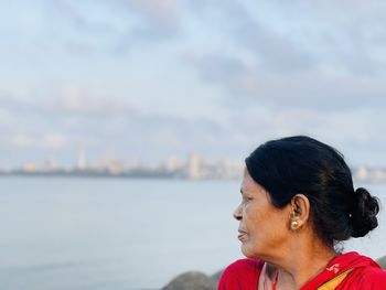 Portrait of woman looking at sea against sky