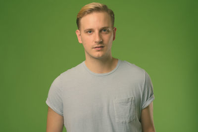 Portrait of young man standing against gray background