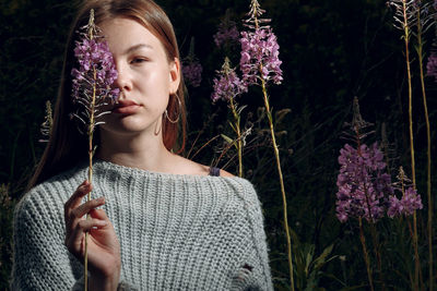 Portrait of beautiful young woman against purple flowering plants