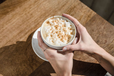 High angle view of woman holding coffee cup on table