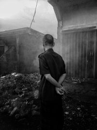 Rear view of man standing by abandoned building