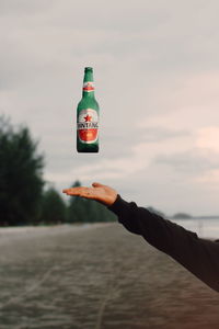 Person holding bottle of water against sky