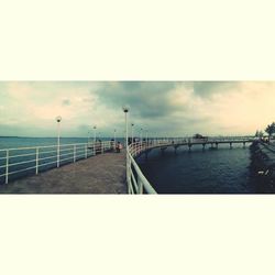 Bridge over calm sea against sky