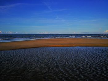 Scenic view of beach against blue sky