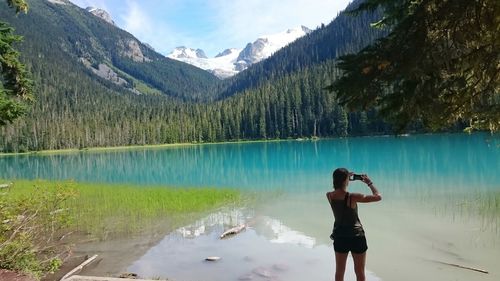 Woman photographing lake against mountains