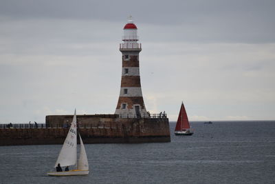 Sailboat sailing on sea by building against sky