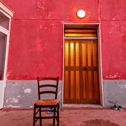 Empty chair against closed door of building