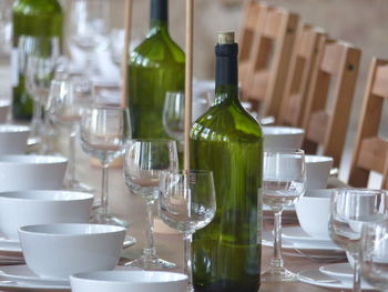 Wineglasses with bowls arranged by wine bottles on table