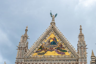 Low angle view of detail of siena dome facade with statue against sky