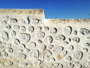 Low angle view of wall against clear blue sky