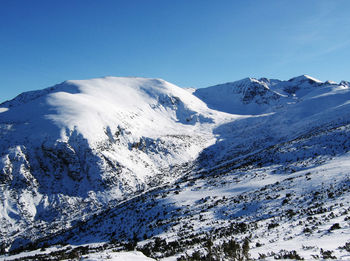 Scenic view of snowcapped mountains against clear blue sky