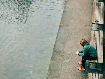 High angle view of man sitting on bench by river