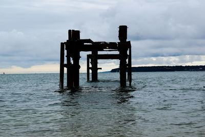 Pier on sea against cloudy sky