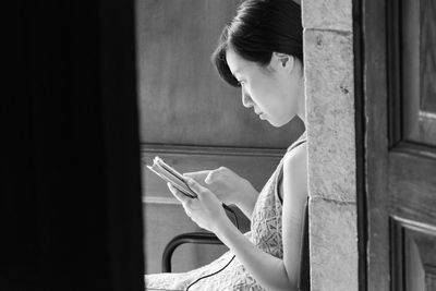 Side view of woman using phone while sitting at home