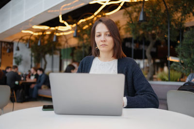 Woman using laptop sitting at cafe