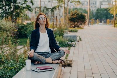 Portrait of young woman sitting on footpath