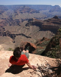 Rear view of man sitting on rock