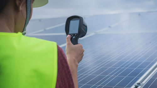 Man holding smart phone against sky