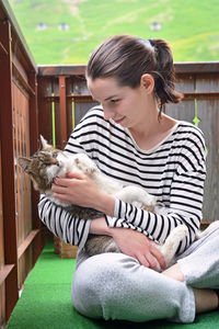 Full length of man holding cat sitting outdoors
