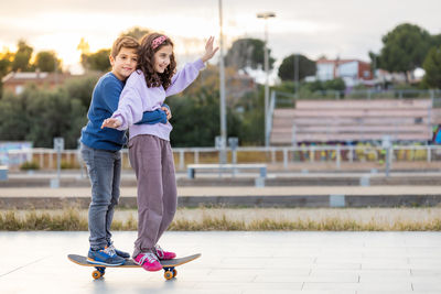 Two kids riding together wtih a skate board