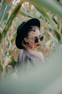 Portrait of young woman in sunglasses standing amidst plants