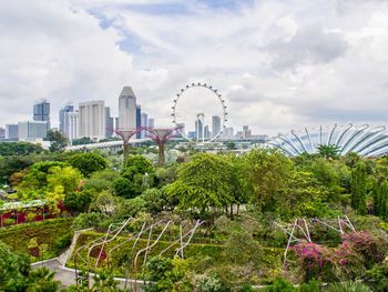 View of ferris wheel in city against cloudy sky