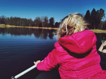 Rear view of woman sitting by pink lake