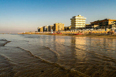 Sea and buildings against clear sky