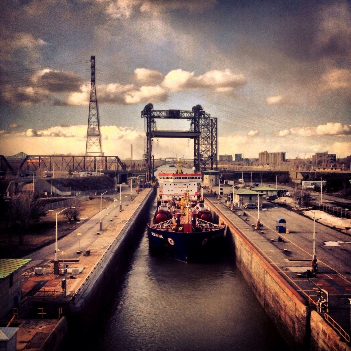 sky, cloud - sky, transportation, architecture, water, built structure, building exterior, cloudy, city, river, nautical vessel, mode of transport, sunset, harbor, cloud, waterfront, connection, bridge - man made structure, dusk, crane - construction machinery