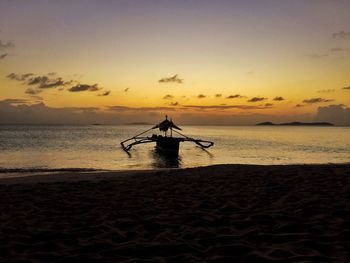 Silhouette person on beach against sky during sunset