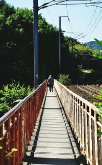 Rear view of woman walking on footbridge