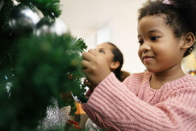 Mother and girl in illuminated christmas tree