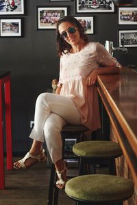 Portrait of woman sitting on stool at bar