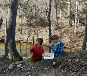 Children sitting on tree trunk in forest