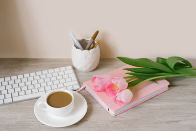 Pink tulips with a festive spring mood and coffee on a wooden table women's work, home office
