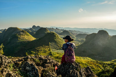 Rear view of woman looking at mountains against sky