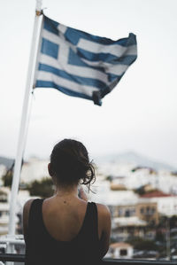 Rear view of woman standing against greek flag in city