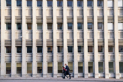 People walking by modern building in city