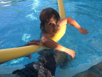 Portrait of shirtless boy by father in swimming pool