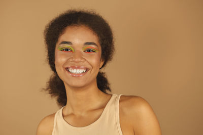 Portrait of young woman against yellow background