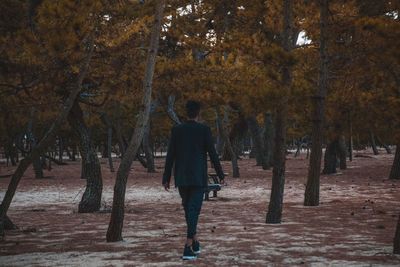 Rear view of man walking at park during autumn