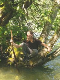 Young woman sitting on tree trunk in forest