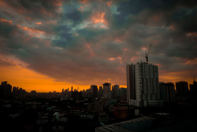 Buildings in city against cloudy sky during sunset