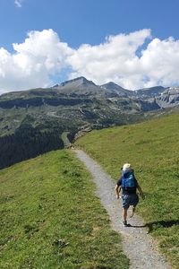 Rear view of man walking on mountain against sky