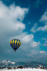 Hot air balloon flying over mountain against cloudy sky