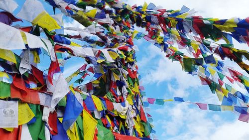 Low angle view of multi colored flags hanging against sky