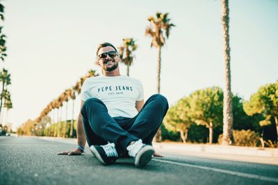 Young man sitting on sunglasses against sky