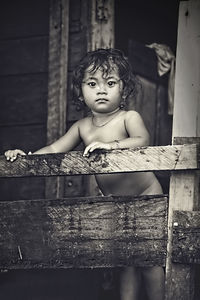 Portrait of shirtless girl standing by railing