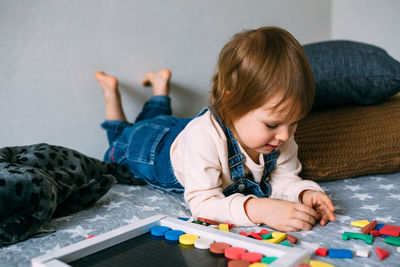 Child plays at home an educational game with a multi-colored magnetic puzzle